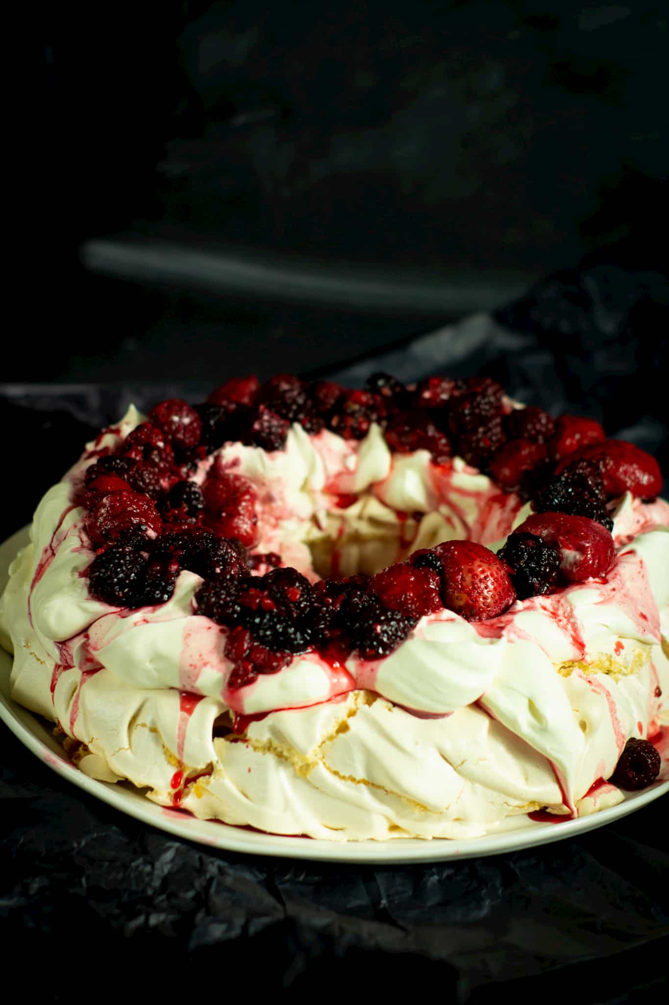 christmas pavlova on a plate with a dark background behind and underneath