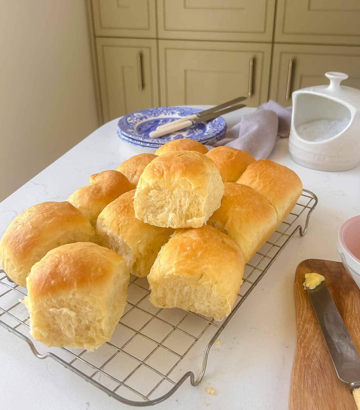 bread rolls on a wire rack with blue and white plates and butter knives in the background