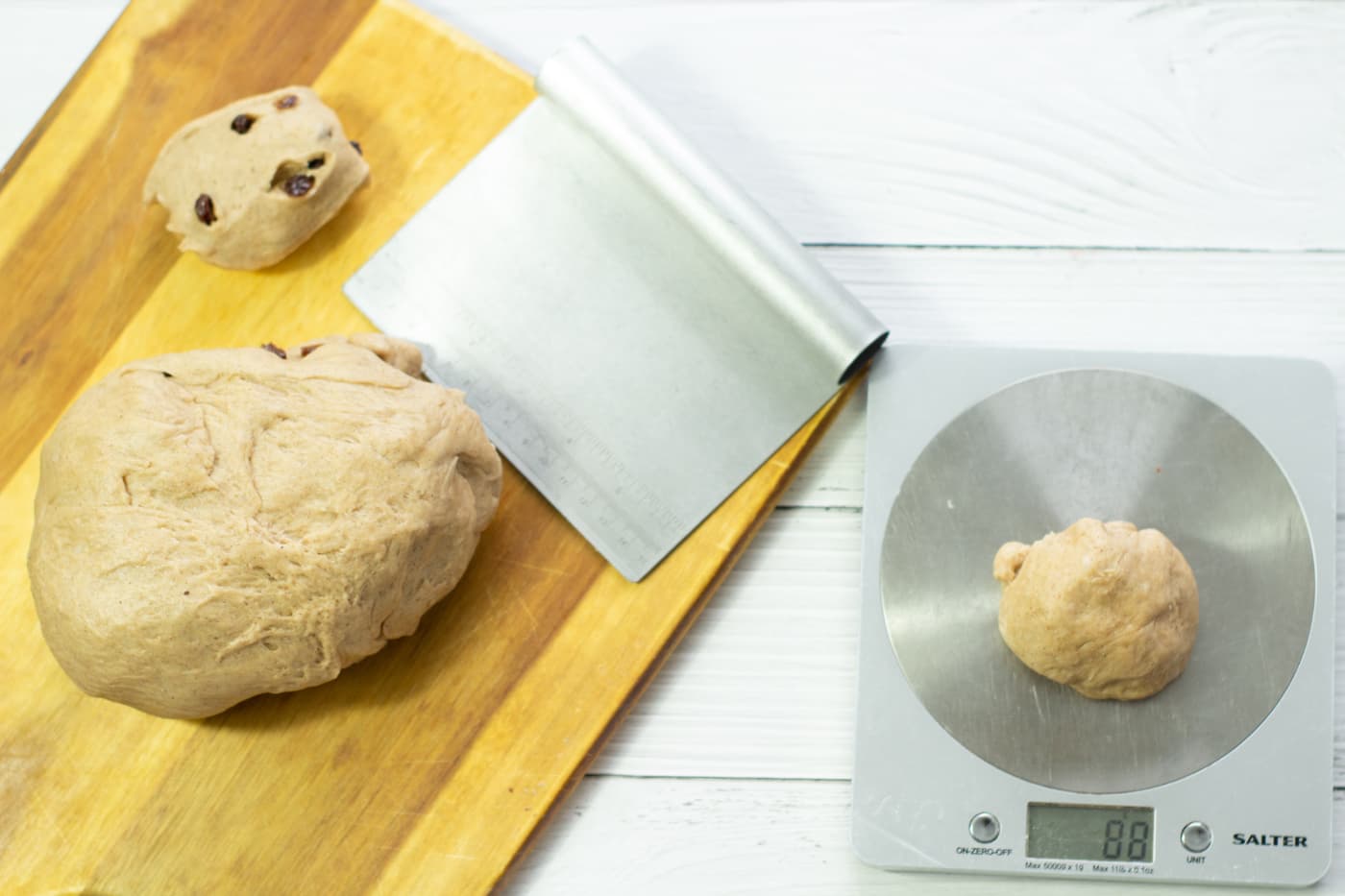 dough on a wooden chopping board with a small aount of dough on digital scales