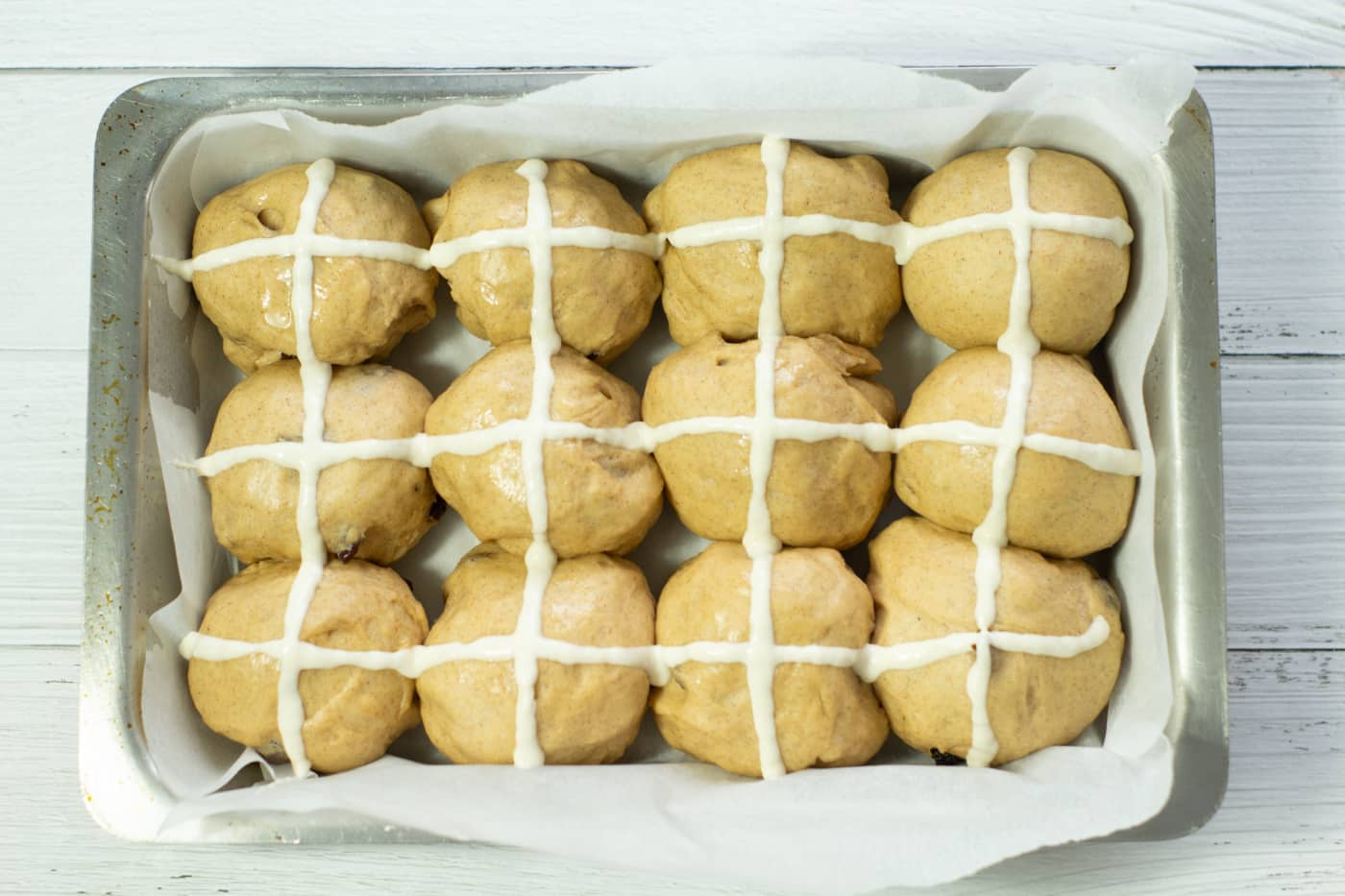 hot cross buns with piped white crosses in a baking tray