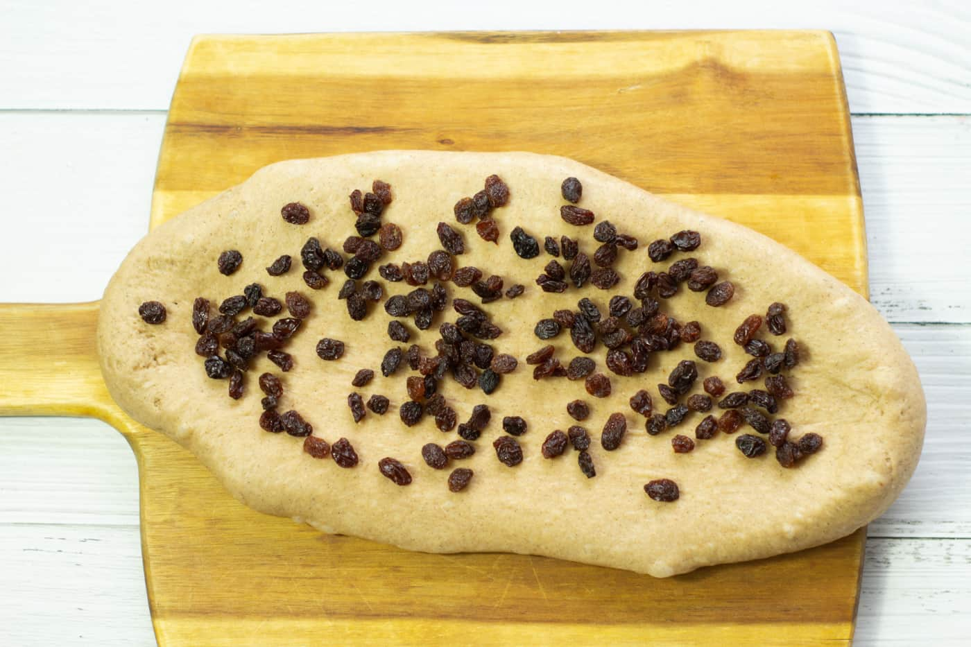 hot cross bun dough rectangle with raisins sprinkled on top.