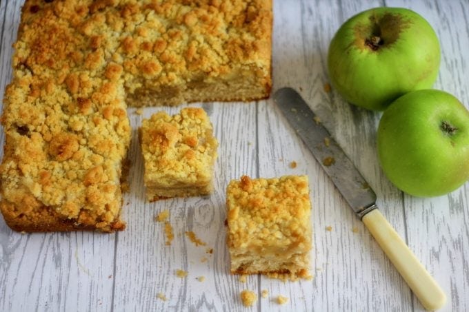 apple crumble cake sliced with apples and a knife nearby
