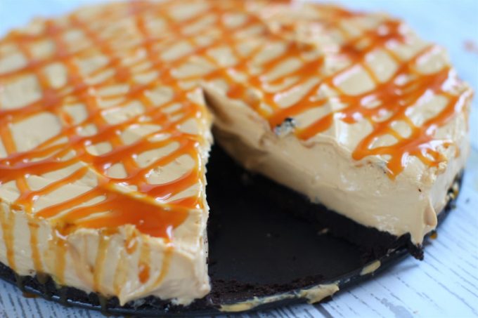 no bake caramel cheesecake with bourbon biscuit base caramel cheesecake with toffee sauce on top, a bourbon biscuit base and a slice missing