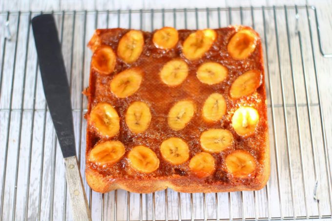 upside down banana cake with a caramel and banana topping on a wire rack