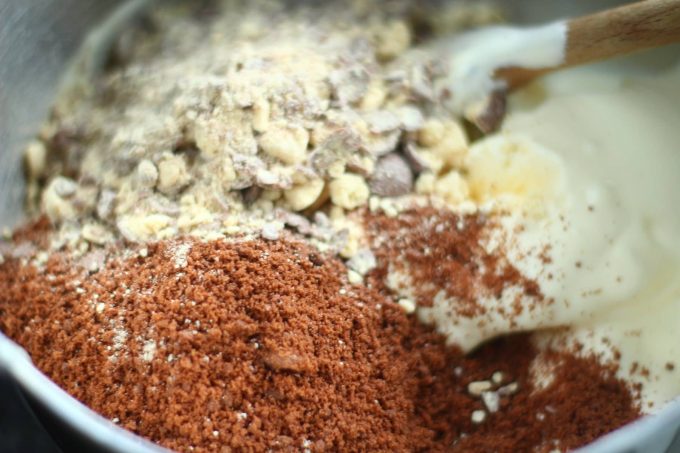 ice cream cake ingredients ice cream topped with chocolate crushed biscuits and maltesers in a bowl with a wooden spoon