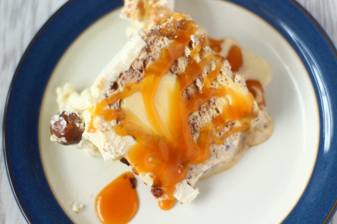 slice of ice cream cake on a blure plate covered in toffee sauce