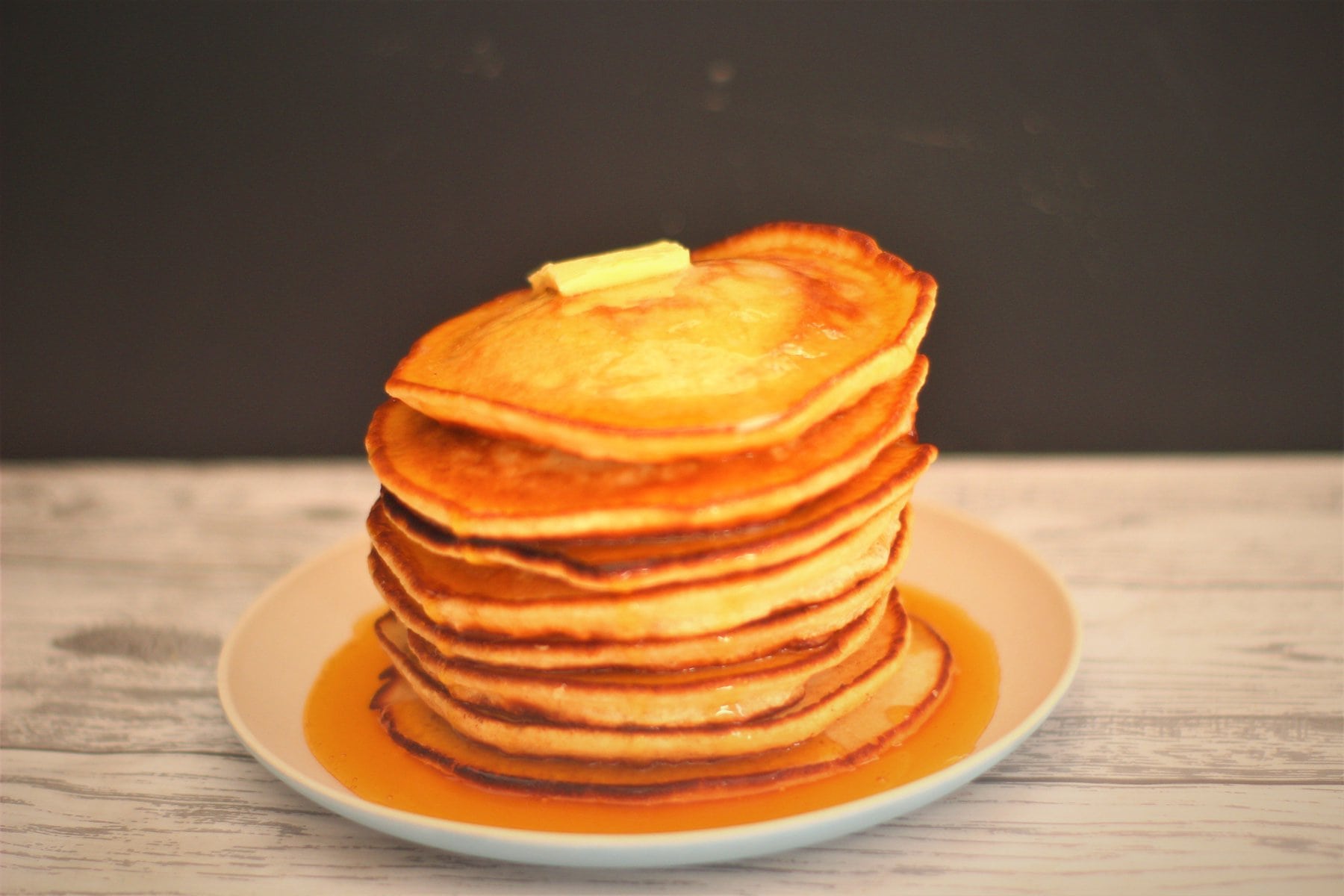 american pancakes american pancakes stacked high on a plate and smothered in syrup