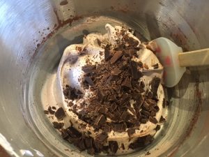 folding in chocolate chunks to the meringue mixture in a mixing bowl
