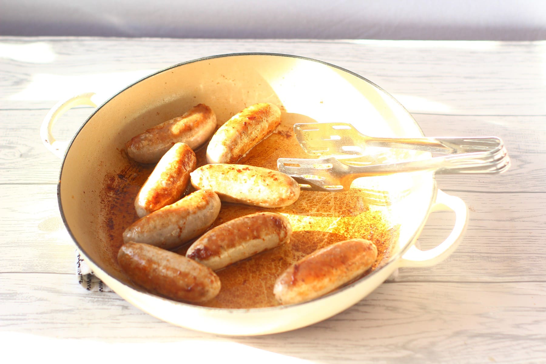 browning sausages in a frying pan