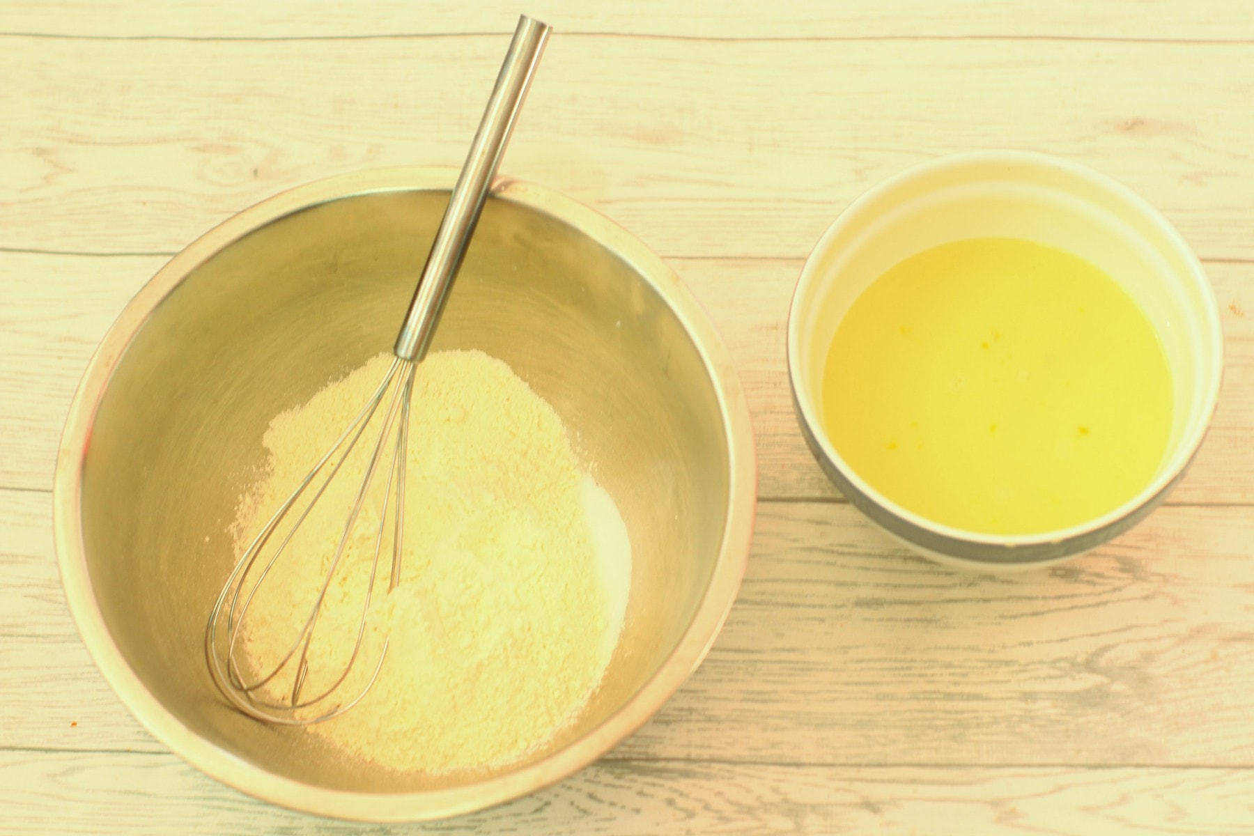 flour and salt in a mixing bowl with a whisk and a jug of eggs and milk