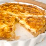 quiche lorraine cut into a wedge in a white flan dish