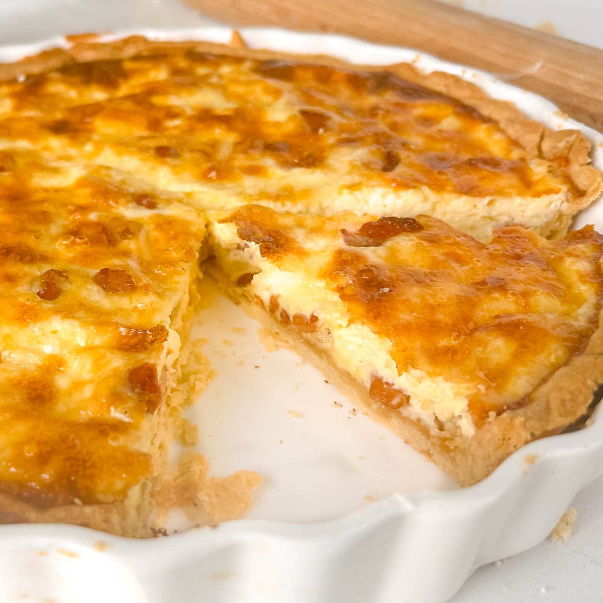 quiche lorraine cut into a wedge in a white flan dish