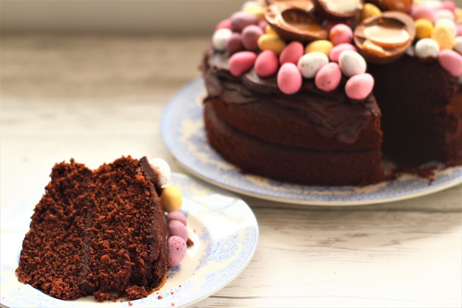slice of easter chocolate cake decorated with mini eggs and larger chocolate eggs