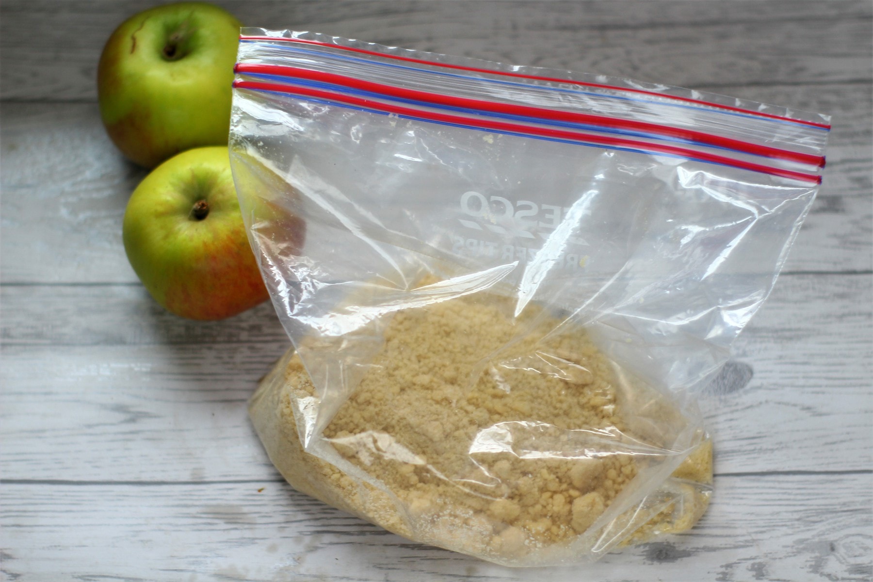 apple crumble crumble topping ready to freeze in a freezer bag with some bramley apples