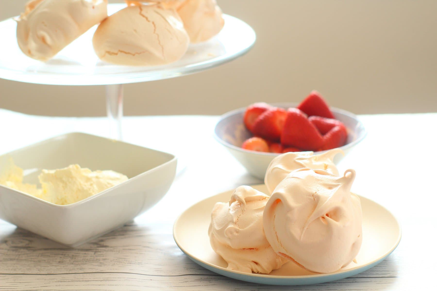 meringues on a plate with strawberries and cream.