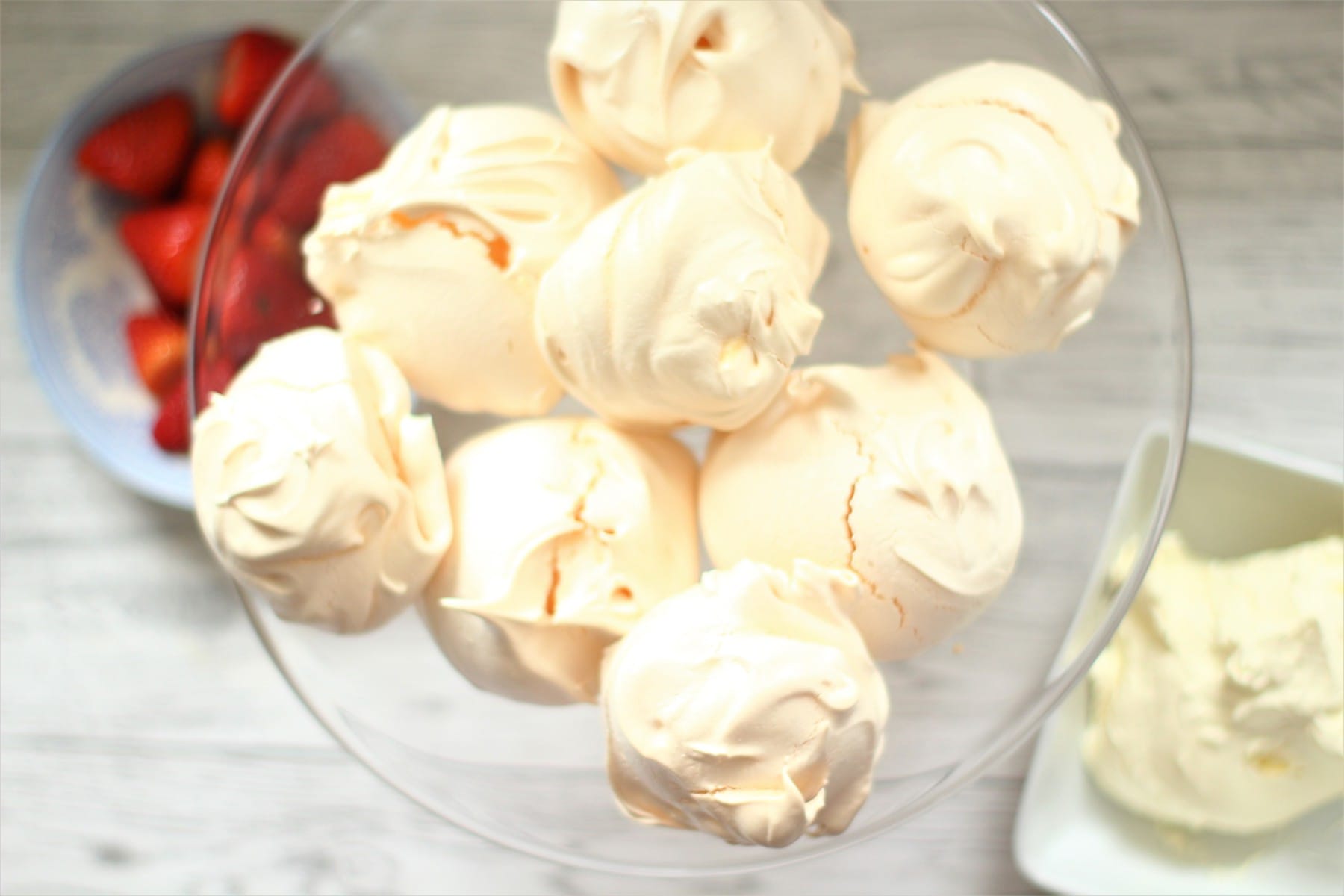 meringues with strawberries and cream in bowls