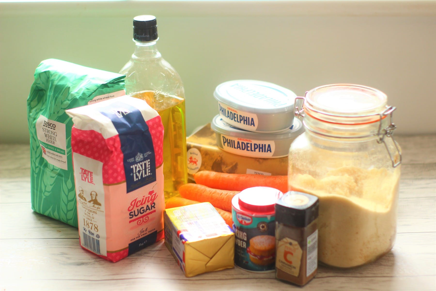 Ingredients for carrot cake traybake recipes-oil, flour, sugar, eggs, carrots, baking powder, cinnamon, cream cheese, butter, icing sugar tray bake ingredients