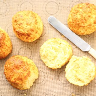 cheese scones on a baking tray with a scone sliced open