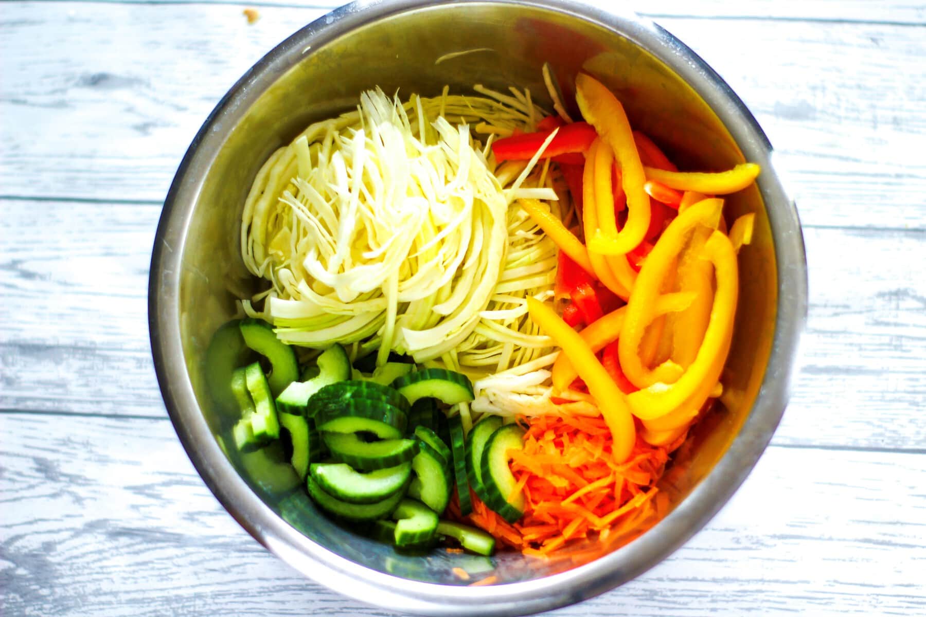 chopped peppers,cabbage,cucumbers and carrots in a bowl