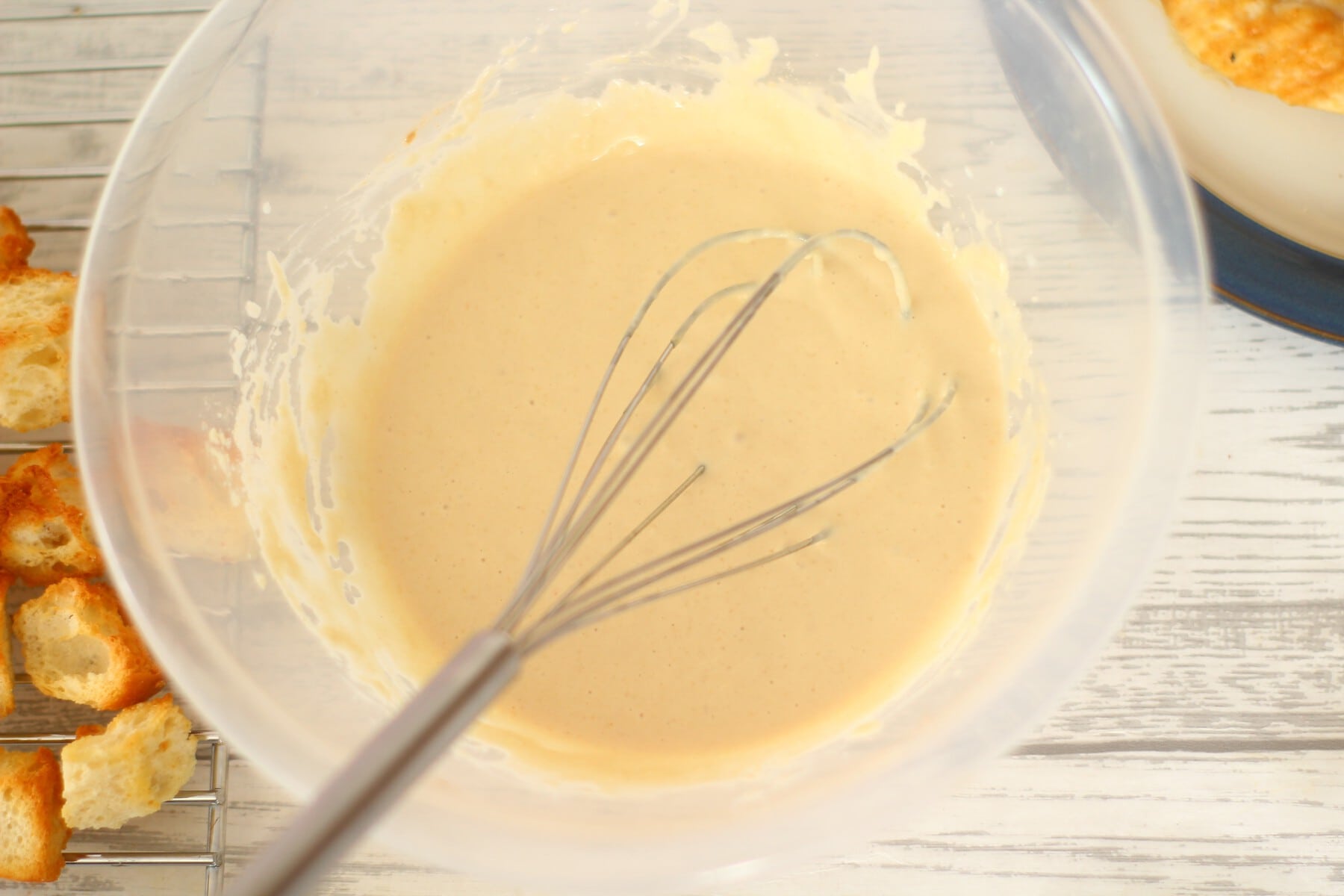 Caesar salad dressing in a bowl with a whisk