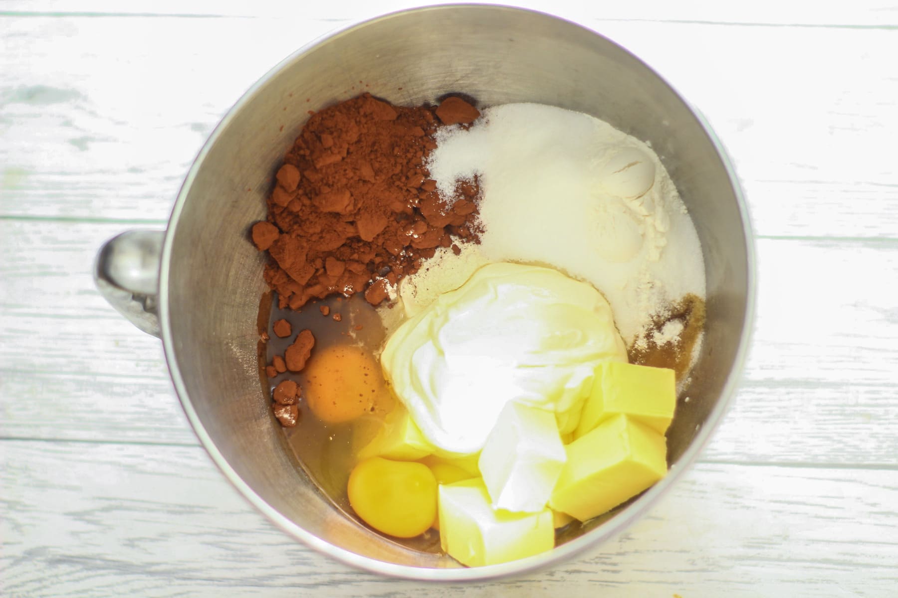 eggs, flour, cocoa, sugar, oil, butter, sour cream, vanilla extract, baking powder, bicarbonate of soda in a mixing bowl