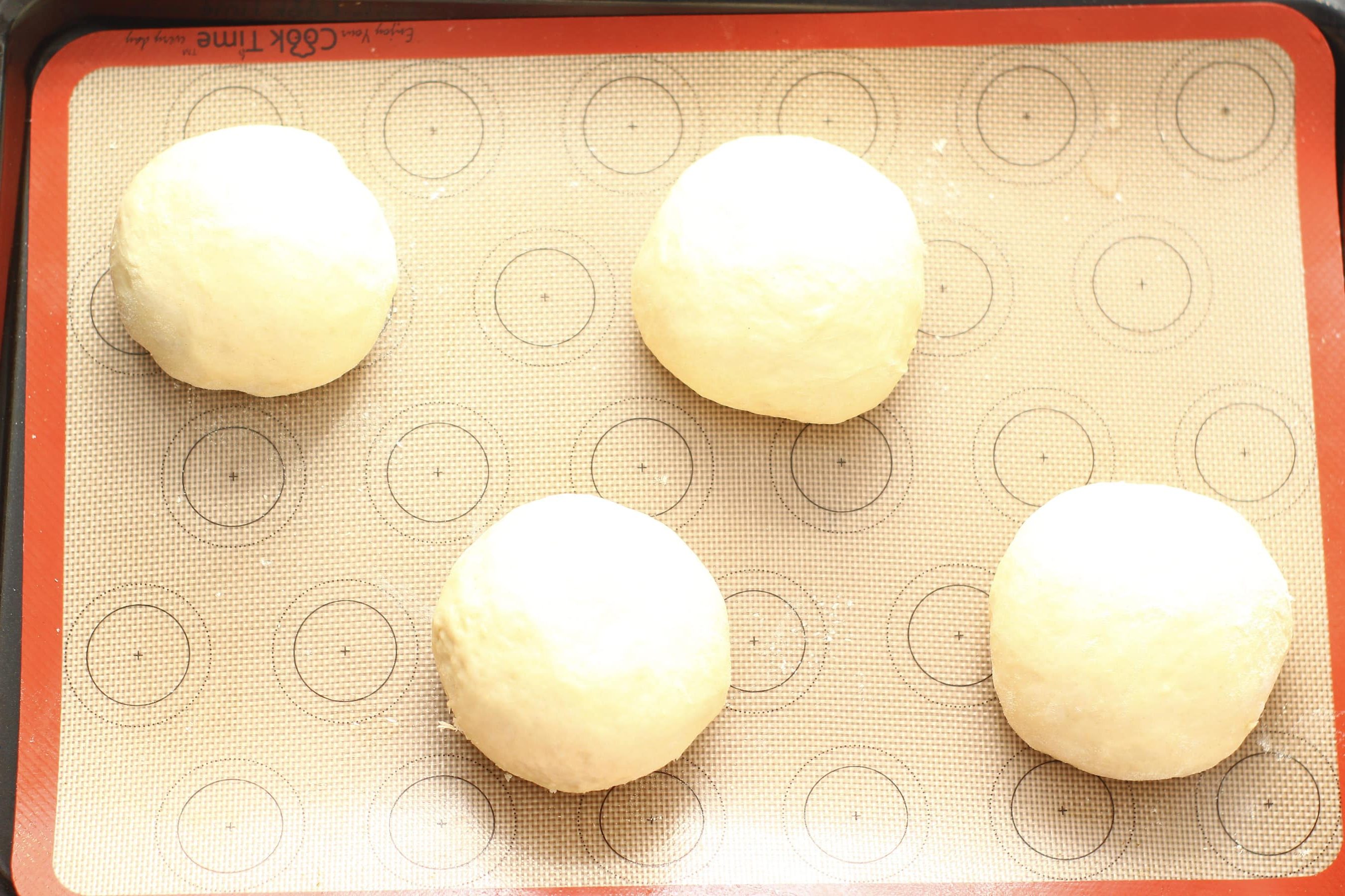 4 bread baps on a baking tray ready to prove