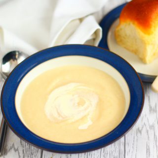 bowl of celeriac soup with a bread roll on a side plate