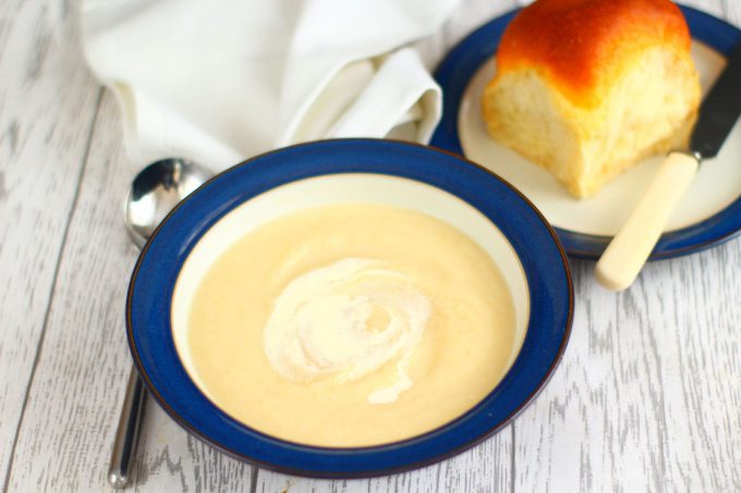 bowl of celeriac soup with a bread roll on a side plate