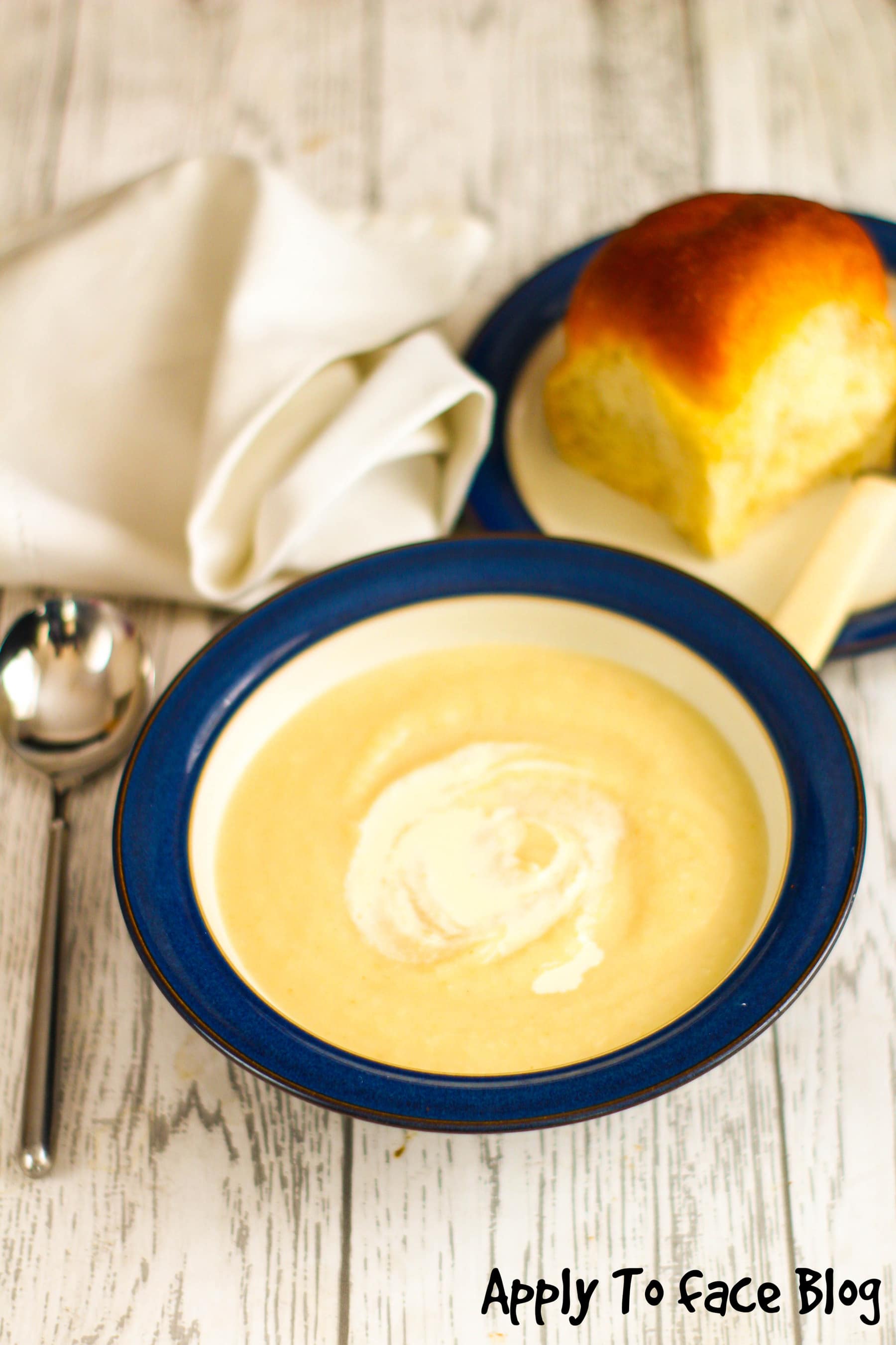 bowl of celeriac soup with a bread roll on a side plate