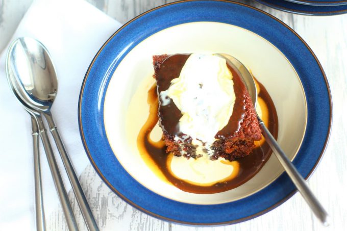 sticky toffee pudding in a bowl with toffee sauce and cream