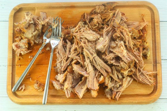 shredded pork on a chopping board with two forks