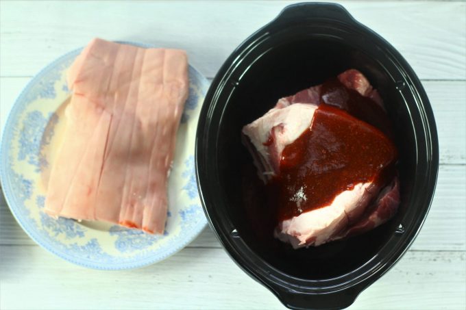 pork shoulder joint in the slow cooker with bbq sauce poured on top