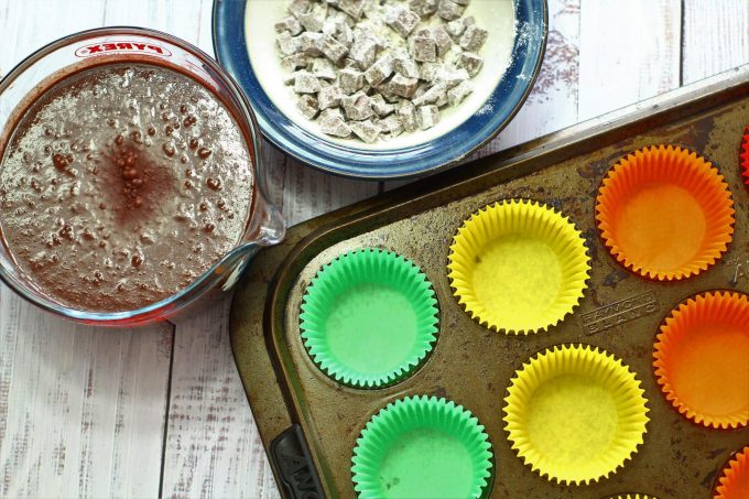 chocolate cupcake batter in a jug with chocolate chunk and empty paper cases in a muffin tray
