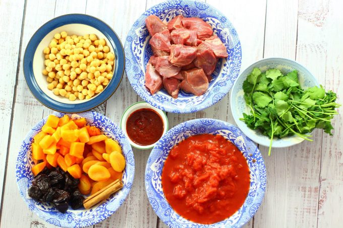 lamb, chick peas, prunes, apricots, harissa, tomatoes and coriander in bowls.