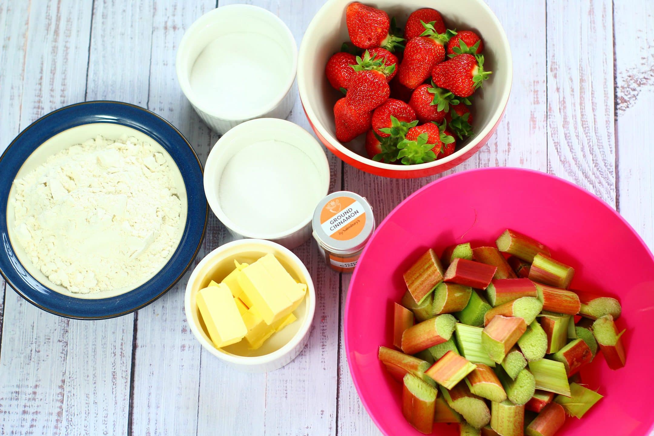 strawberries, rhubarb, sugar, butter, ground cinnamon, in bowls on a table