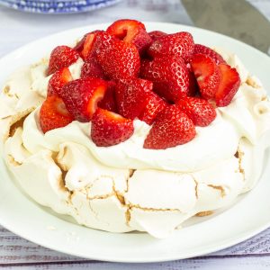 pavlova topped with softly whipped cream and strawberries