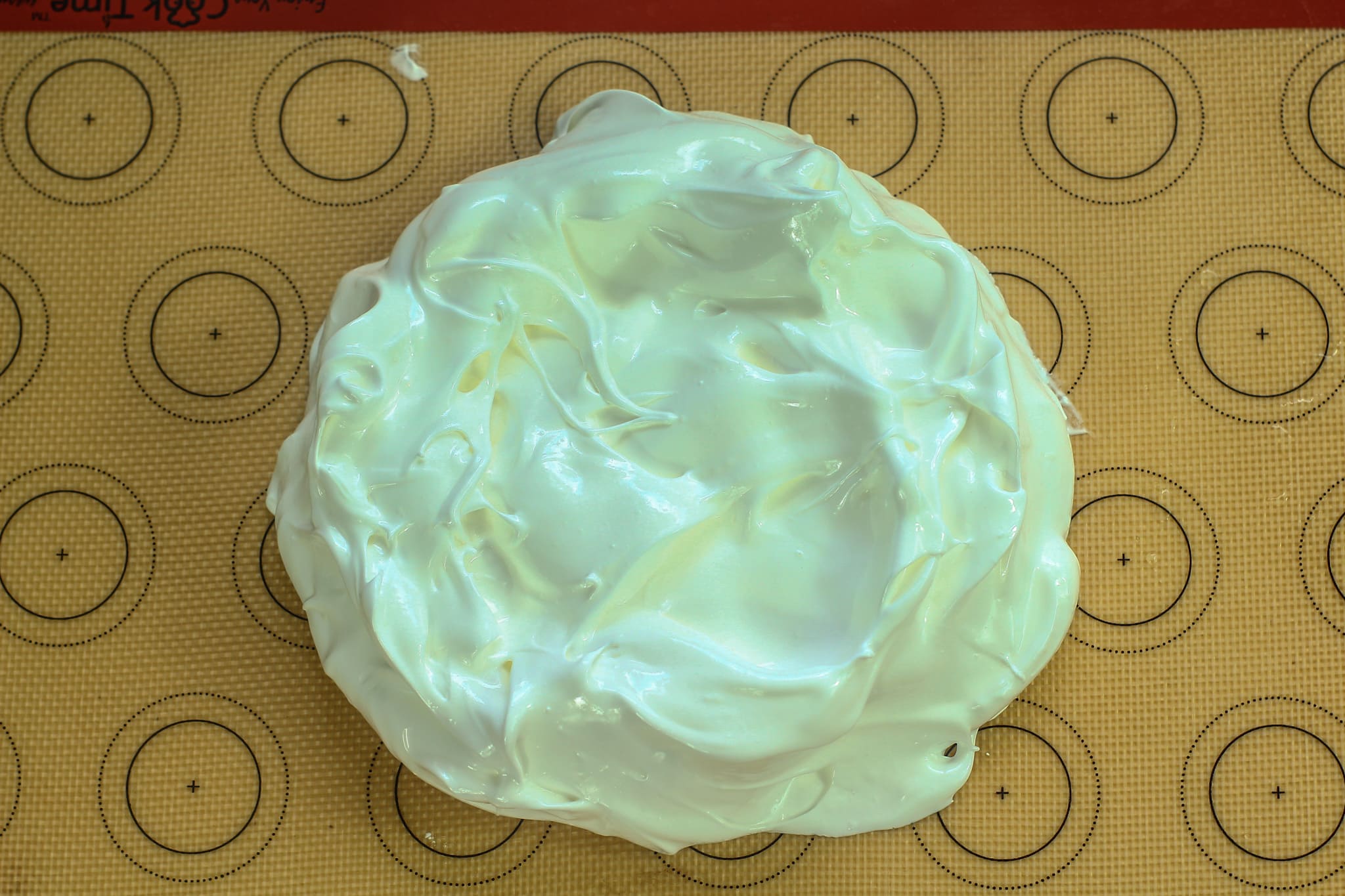 raw meringue mixture in a circle on a lined baking tray.