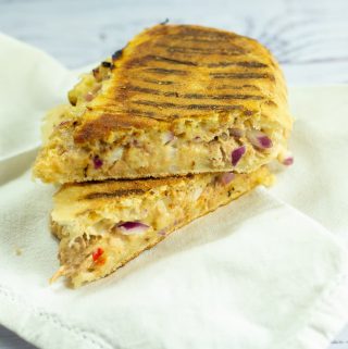tuna melt panini cut in half and piled on top of each other on a white napkin