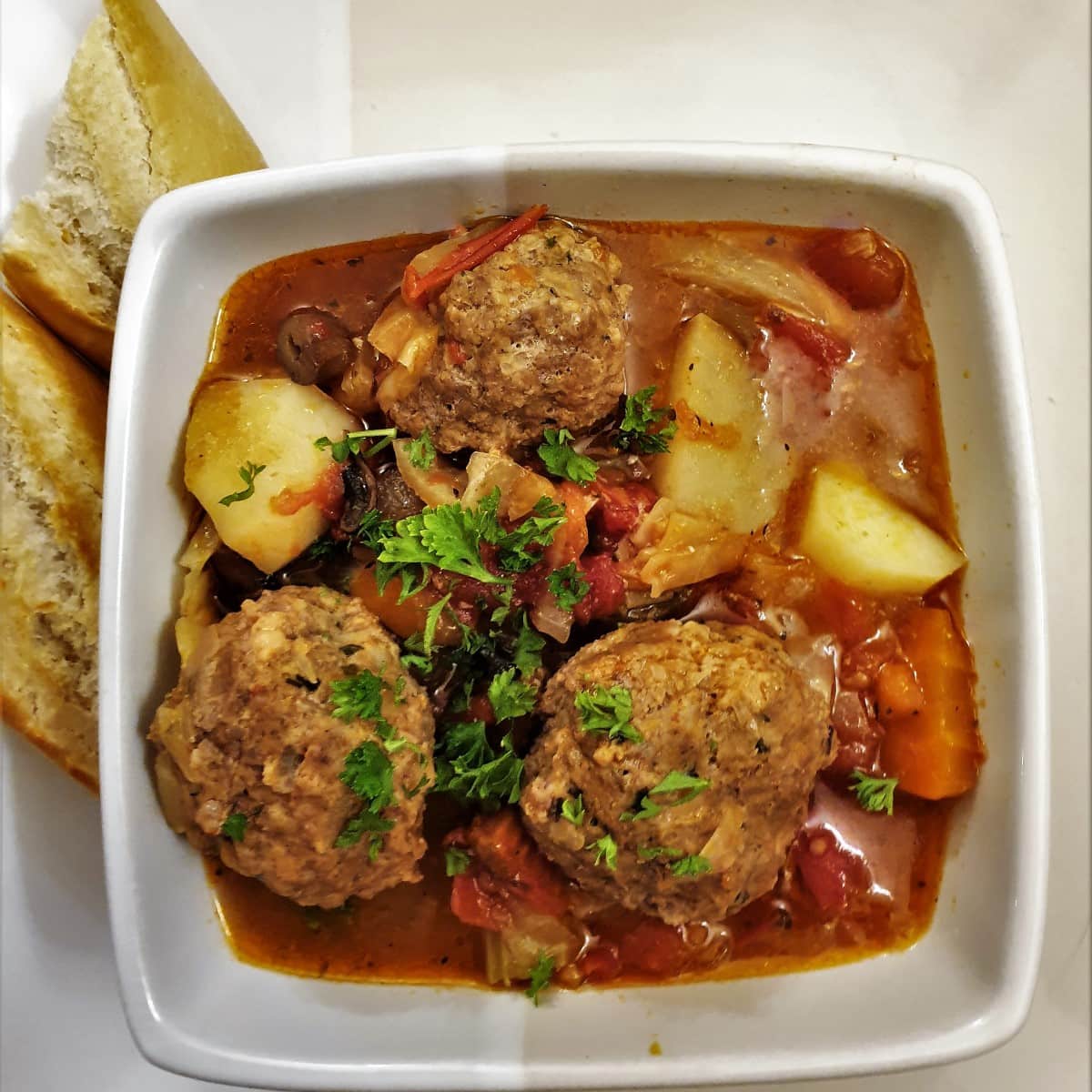 meatball soup in a bowl with bread to the side