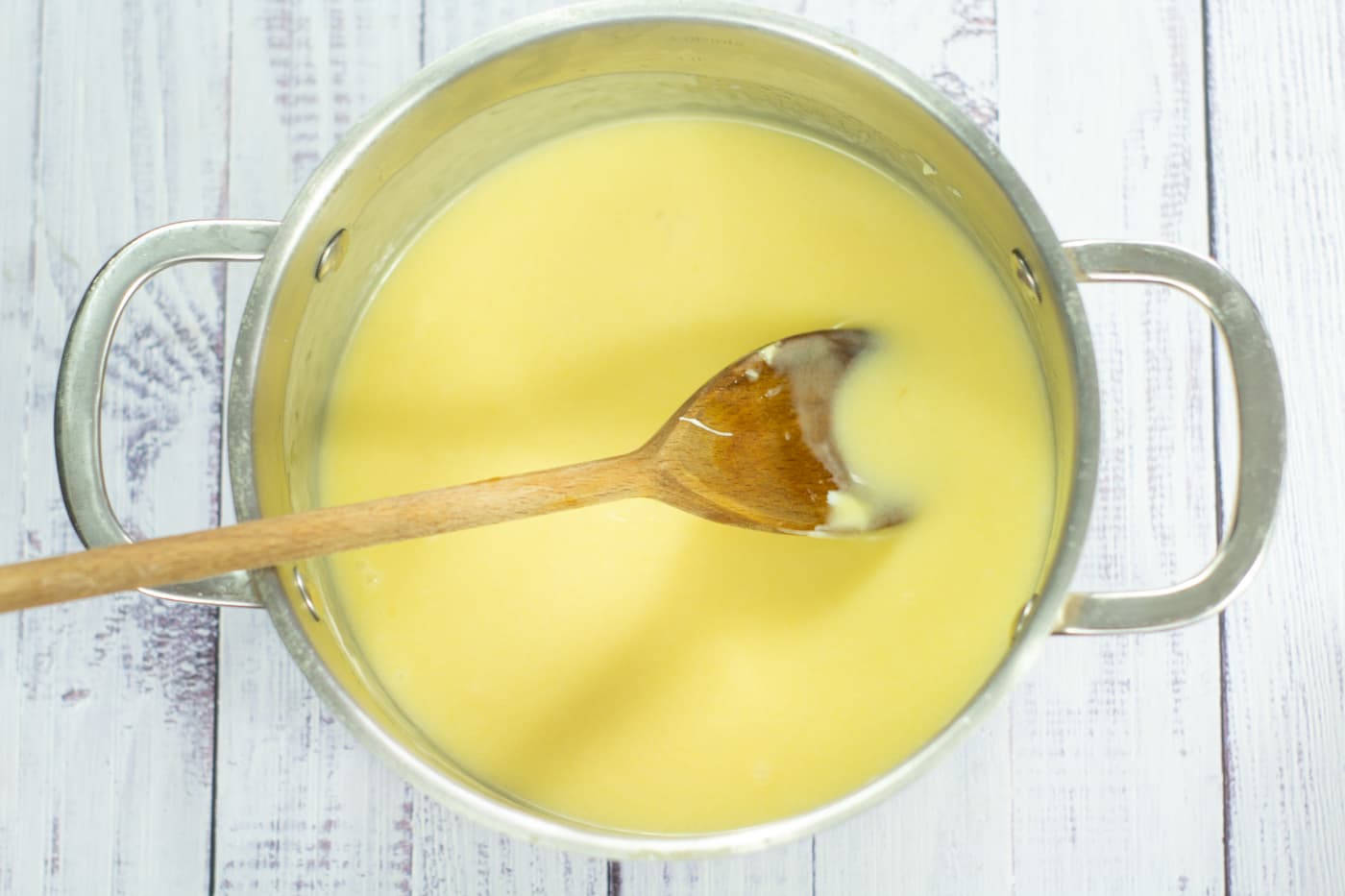 pale cake mixture in a saucepan with a wooden spoon