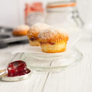 easy jam duffins on a glass plate with a spoon of jam in the front and glass jars behind