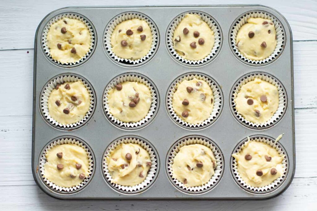 chocolate chip muffins batter in a 12 hole muffin tray