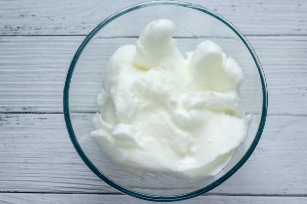 frothy egg whites in a glass bowl.
