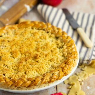 apple crumble pie with a striped napkin and knife to the upper right and a rolling pin to the left