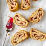 jam roly poly slices on white baking paper with a jammy spoon to one side